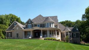 A large house in the distance with gray roofing and lots of windows.