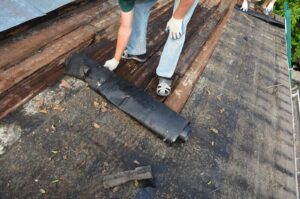 Worker repairing a roof while wearing gloves on his hand