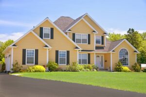 A large home with yellow siding and black window shutters.